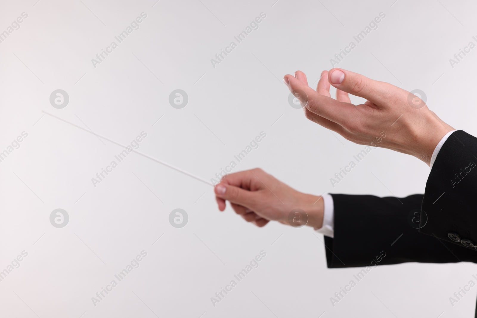 Conductor with baton on light grey background, closeup Photo of Conductor with baton on light grey background, closeup