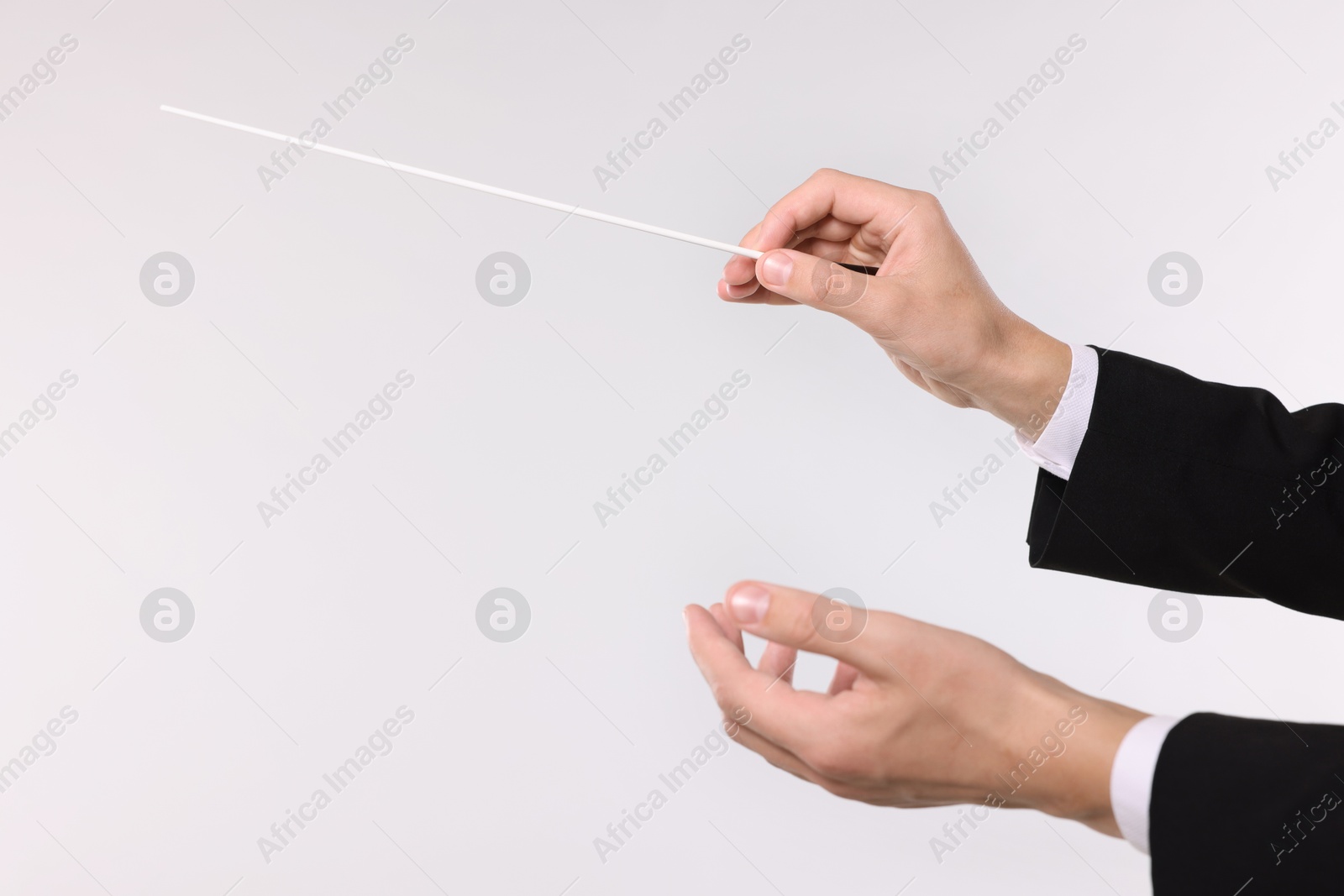 Conductor with baton on light grey background, closeup. Space for text Photo of Conductor with baton on light grey background, closeup. Space for text