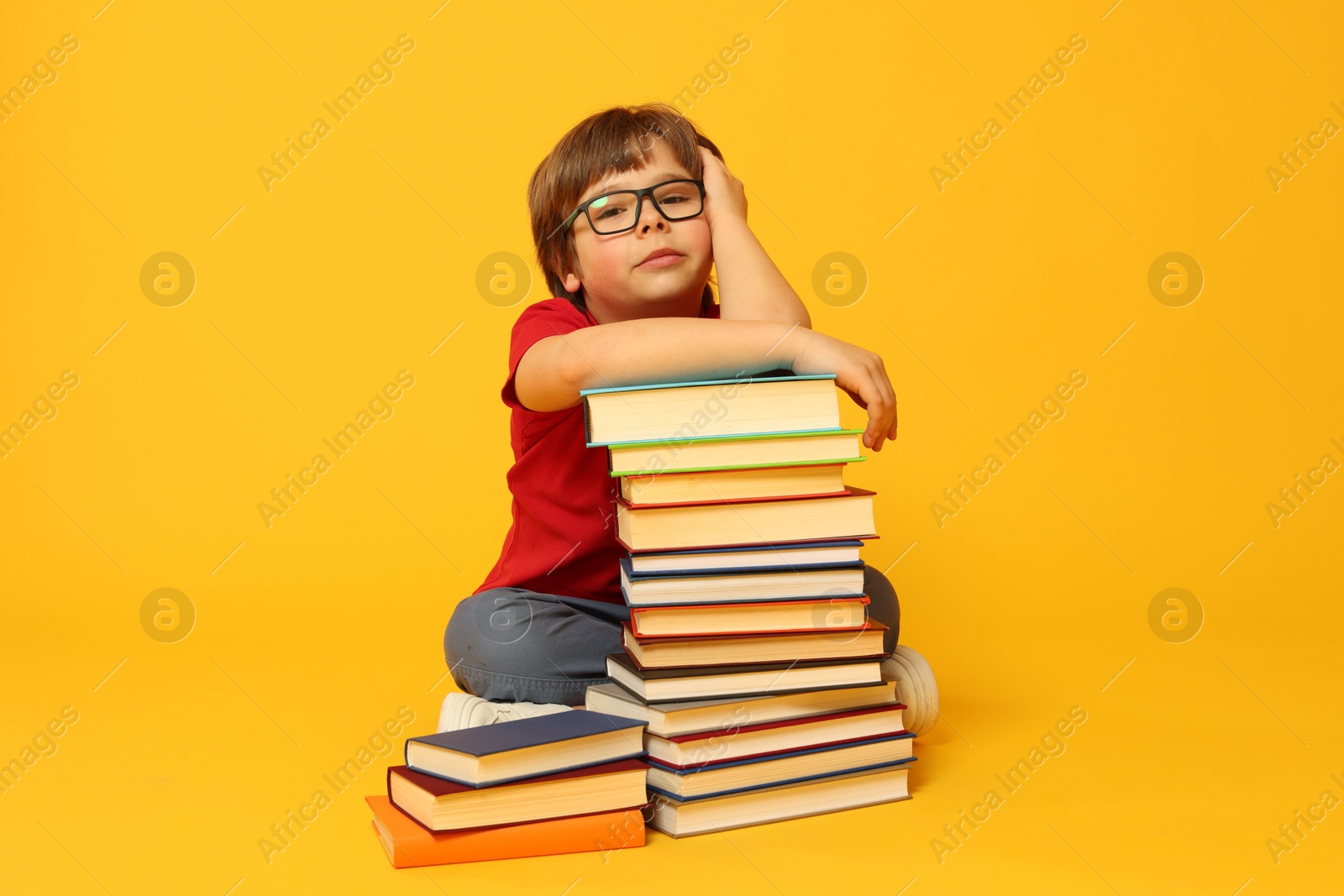 Boy with many different books on orange background Photo of Boy with many different books on orange background