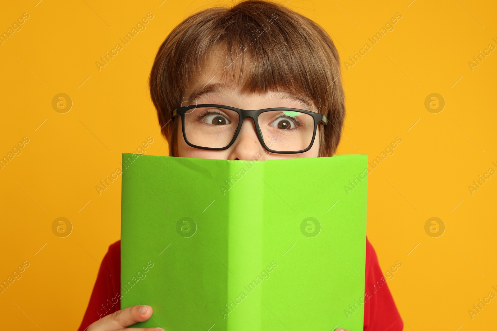 Photo of Little boy with book on orange background