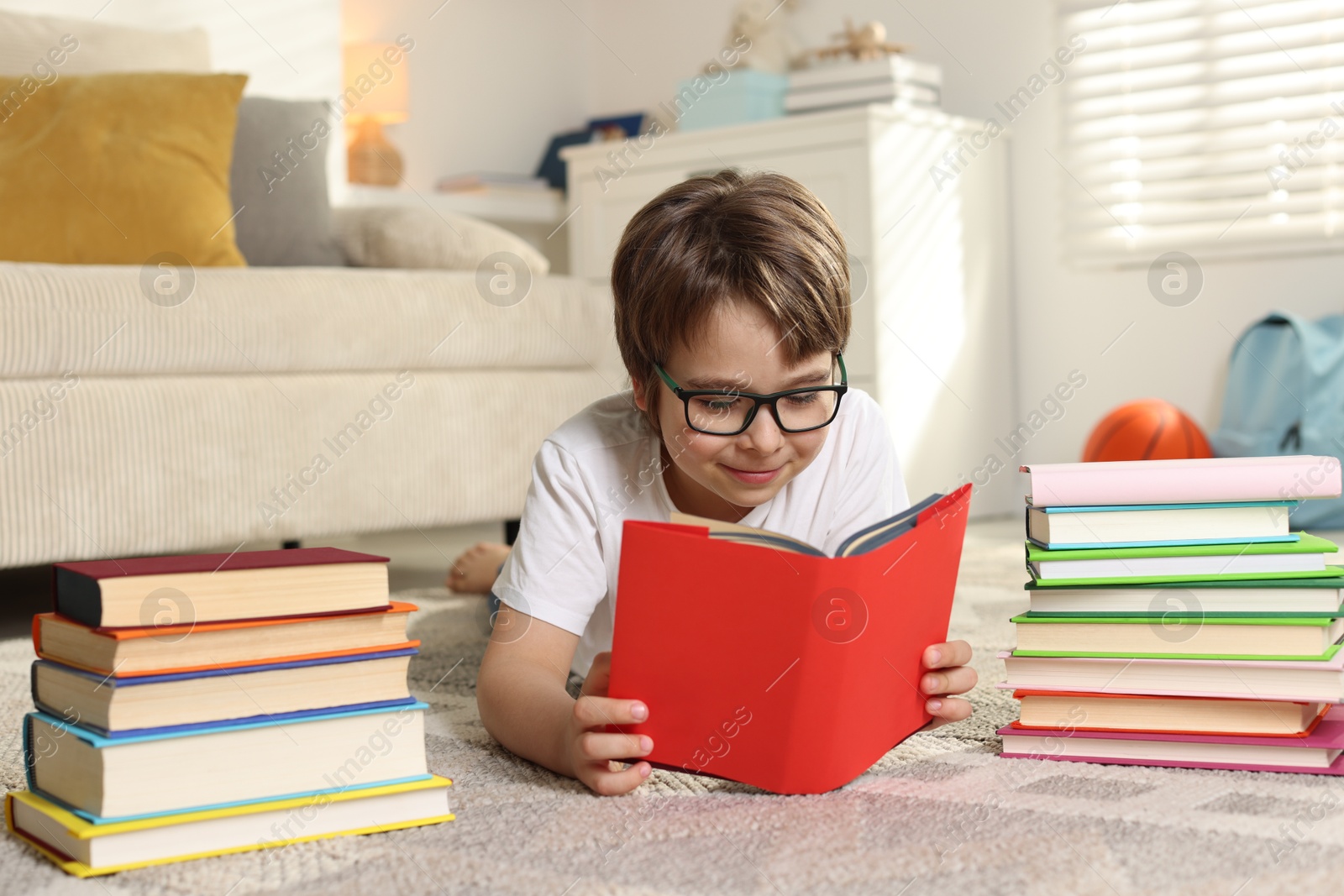 Boy with many different books on floor at home Photo of Boy with many different books on floor at home