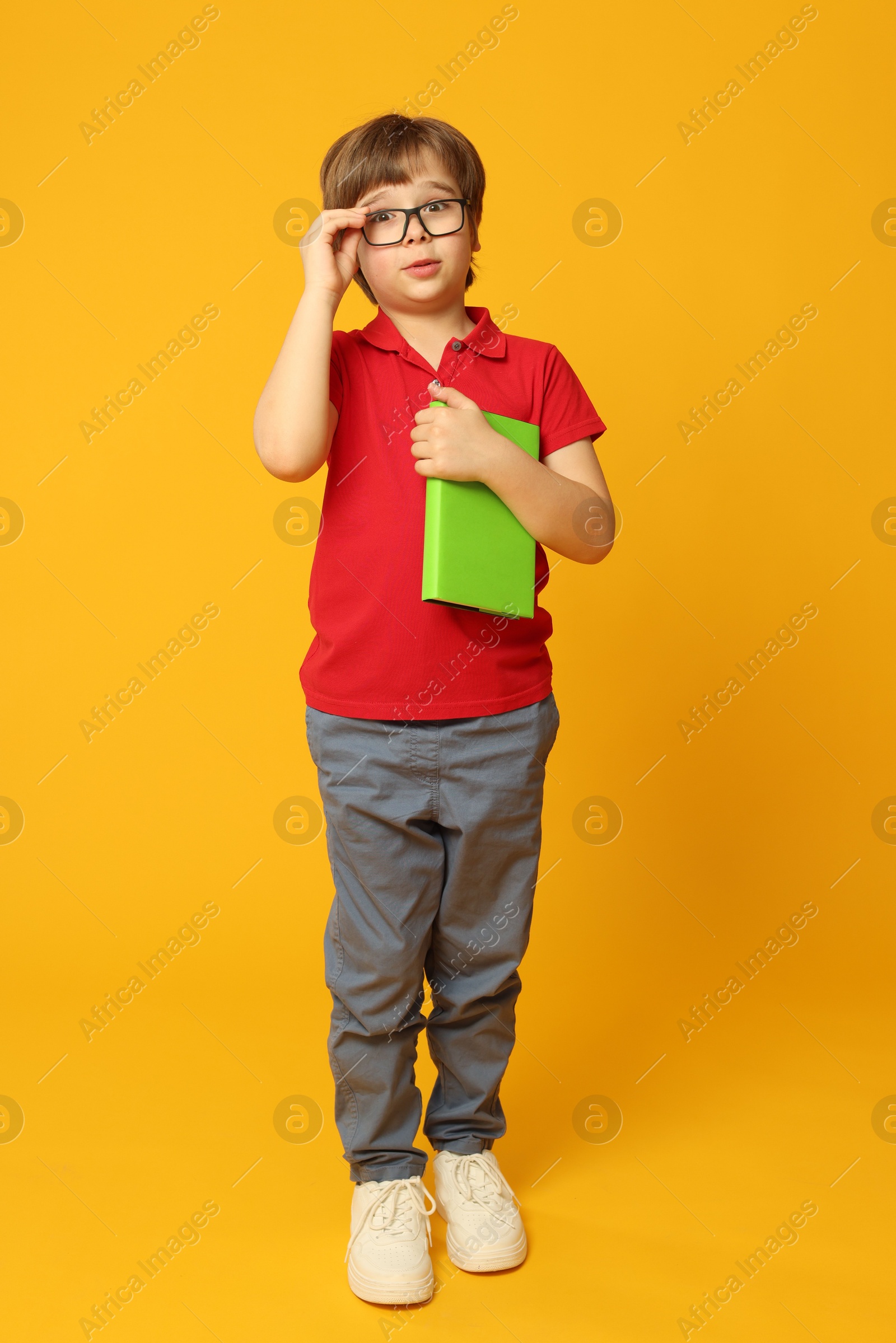 Little boy with book on orange background Photo of Little boy with book on orange background