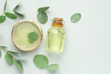 Photo of Bottle of essential oil, bowl and eucalyptus leaves on white background, flat lay. Space for text