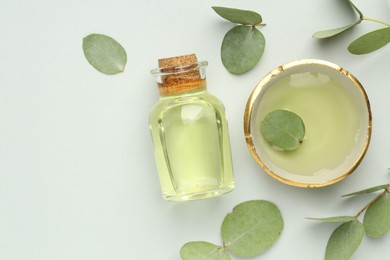 Photo of Bottle of essential oil, bowl and eucalyptus leaves on white background, flat lay. Space for text