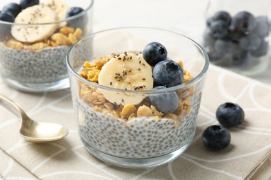 Photo of Delicious dessert with chia seeds, yogurt, granola, blueberries and banana on table, closeup. Superfood