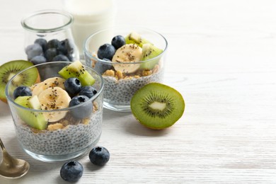 Photo of Superfood. Delicious dessert with chia seeds, yogurt, granola, blueberries, banana and kiwi on white wooden table, closeup. Space for text