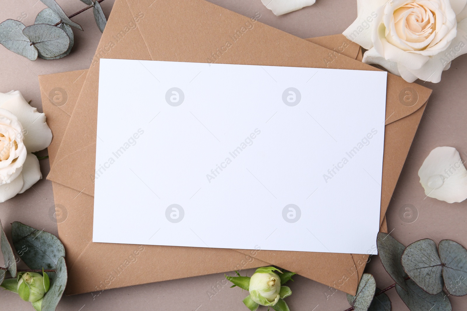Blank greeting card, paper envelopes, rose flowers and eucalyptus branches on beige background, flat lay Photo of Blank greeting card, paper envelopes, rose flowers and eucalyptus branches on beige background, flat lay