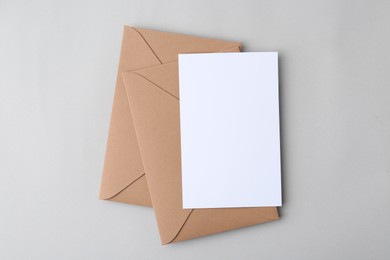Photo of Blank greeting card and paper envelopes on light background, top view