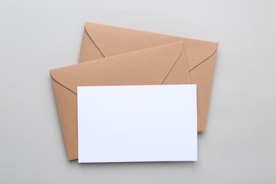Photo of Blank greeting card and paper envelopes on light background, top view