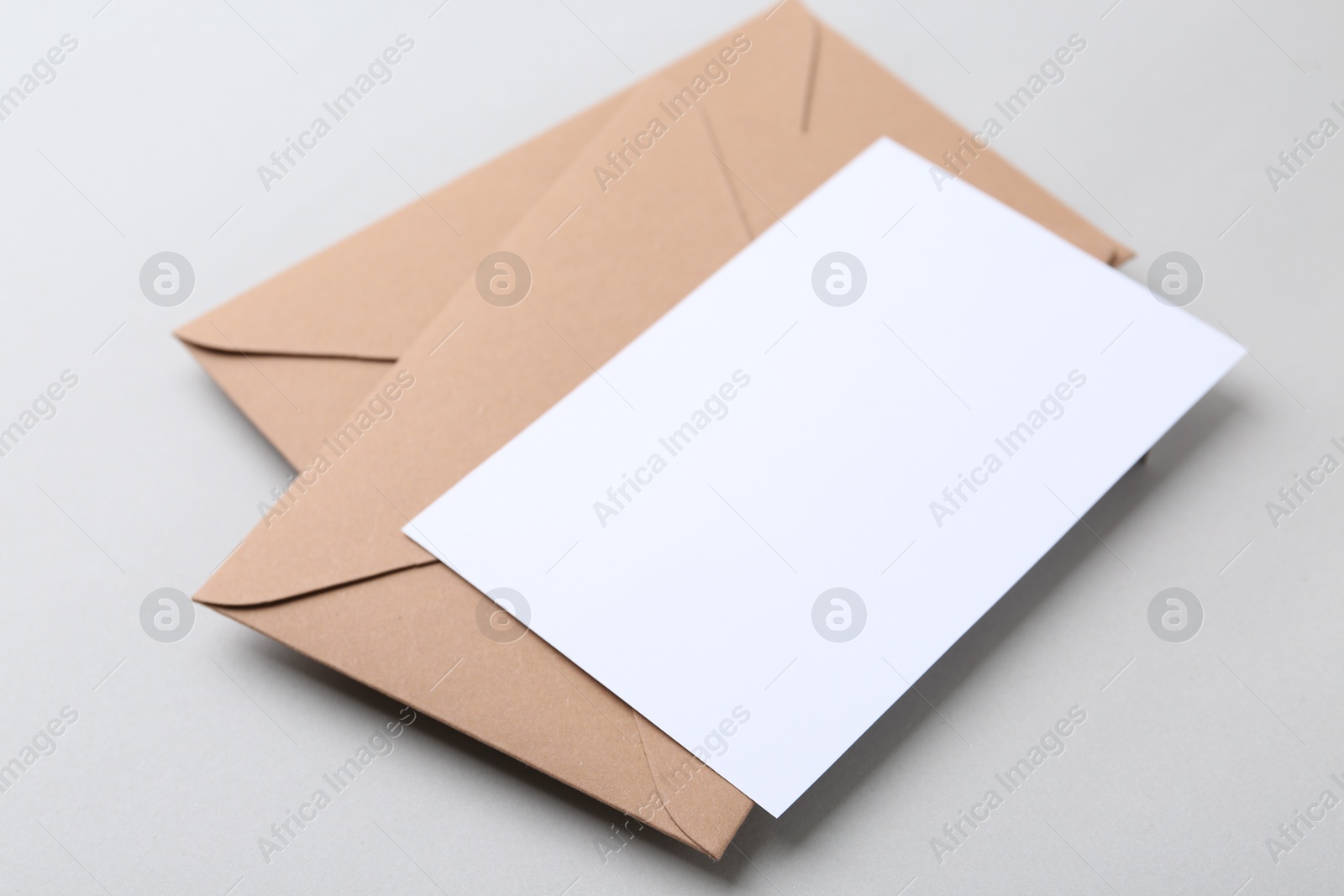 Photo of Blank greeting card and paper envelopes on light background, closeup