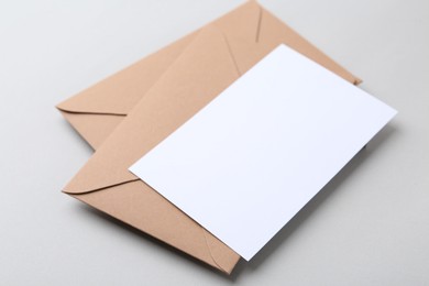 Photo of Blank greeting card and paper envelopes on light background, closeup