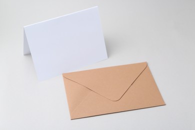 Photo of Blank greeting card and paper envelope on light background