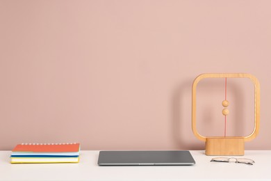 Photo of Laptop, stationery, lamp and glasses on white office table against dark beige background