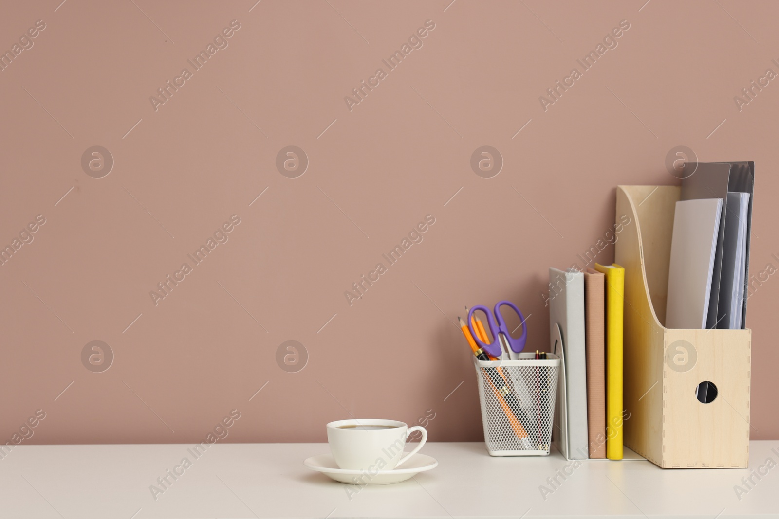 Different stationery and coffee on white office table against dark beige background, space for text Photo of Different stationery and coffee on white office table against dark beige background, space for text