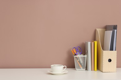 Photo of Different stationery and coffee on white office table against dark beige background, space for text