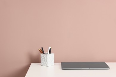 Photo of Laptop and different stationery on white office table against dark beige background