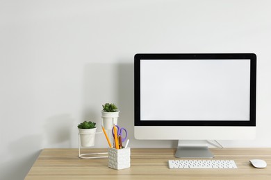 Photo of Computer, keyboard, mouse, different stationery and floral decor on wooden office table against white background