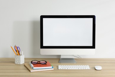 Photo of Computer, keyboard, mouse, different stationery and glasses on wooden office table against white background