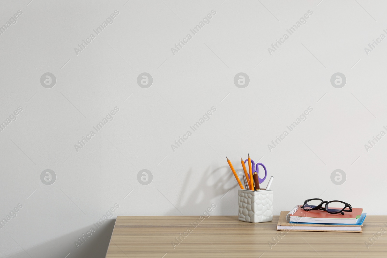 Different stationery and glasses on wooden office table against white background, space for text Photo of Different stationery and glasses on wooden office table against white background, space for text