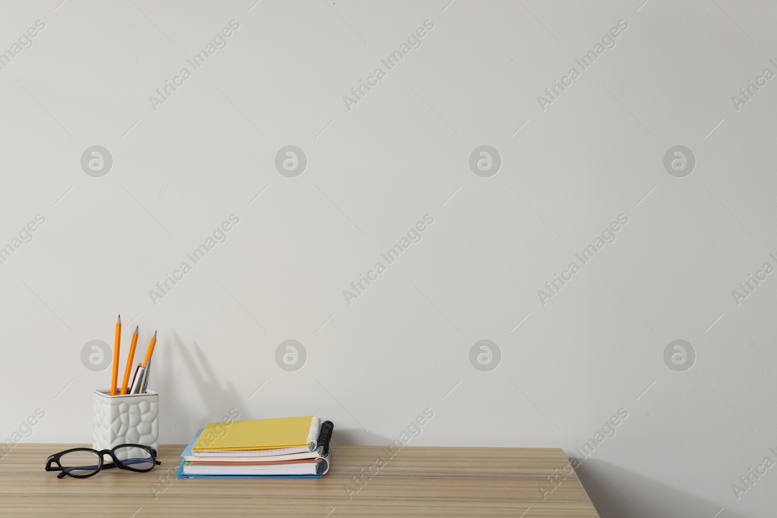 Different stationery and glasses on wooden office table against white background, space for text Photo of Different stationery and glasses on wooden office table against white background, space for text