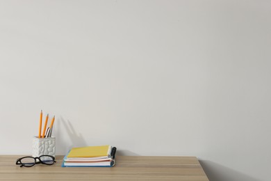 Photo of Different stationery and glasses on wooden office table against white background, space for text