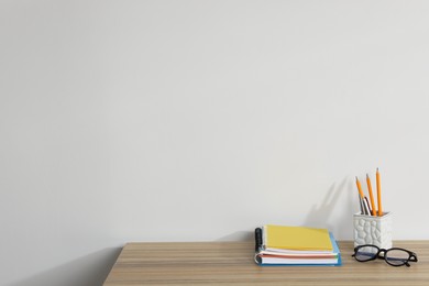 Photo of Different stationery and glasses on wooden office table against white background, space for text