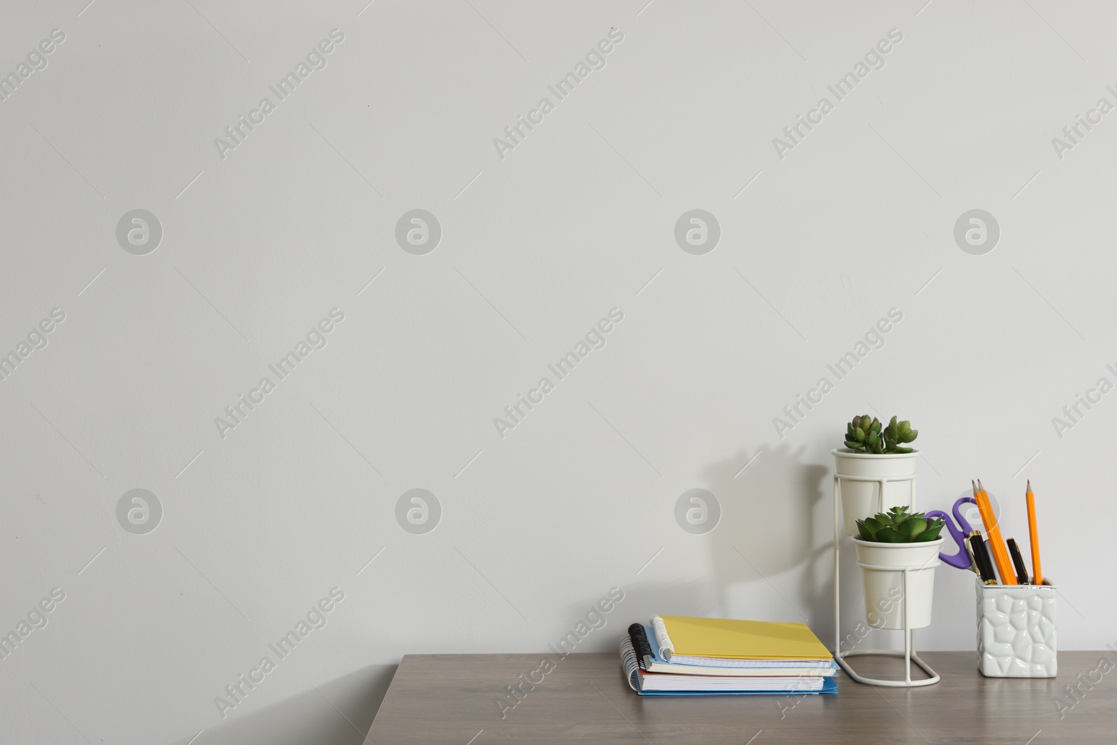 Different stationery and floral decor on wooden office table against white background, space for text Photo of Different stationery and floral decor on wooden office table against white background, space for text