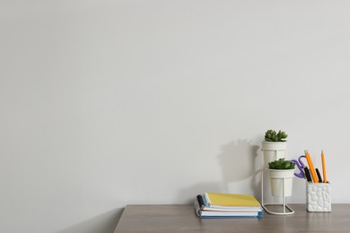 Photo of Different stationery and floral decor on wooden office table against white background, space for text