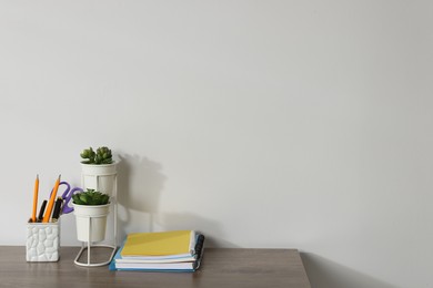 Photo of Different stationery and floral decor on wooden office table against white background, space for text