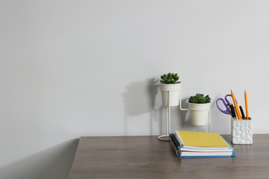 Photo of Different stationery and floral decor on wooden office table against white background, space for text