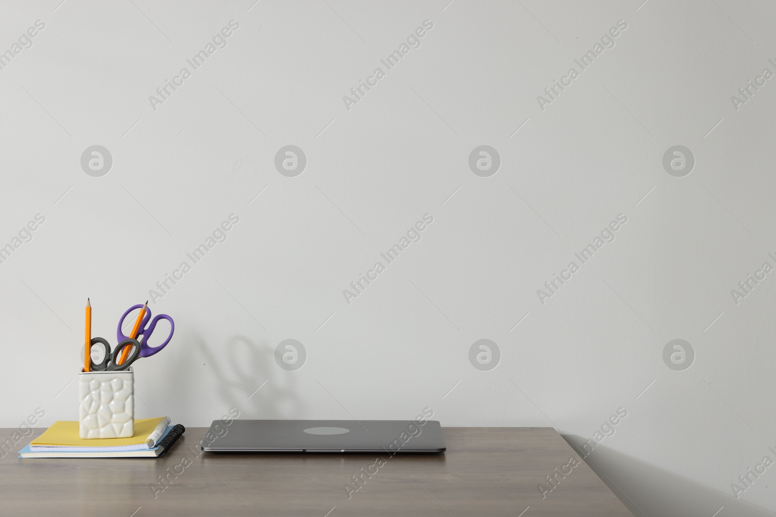 Laptop and different stationery on wooden office table against white background, space for text Photo of Laptop and different stationery on wooden office table against white background, space for text