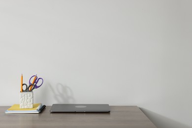 Photo of Laptop and different stationery on wooden office table against white background, space for text