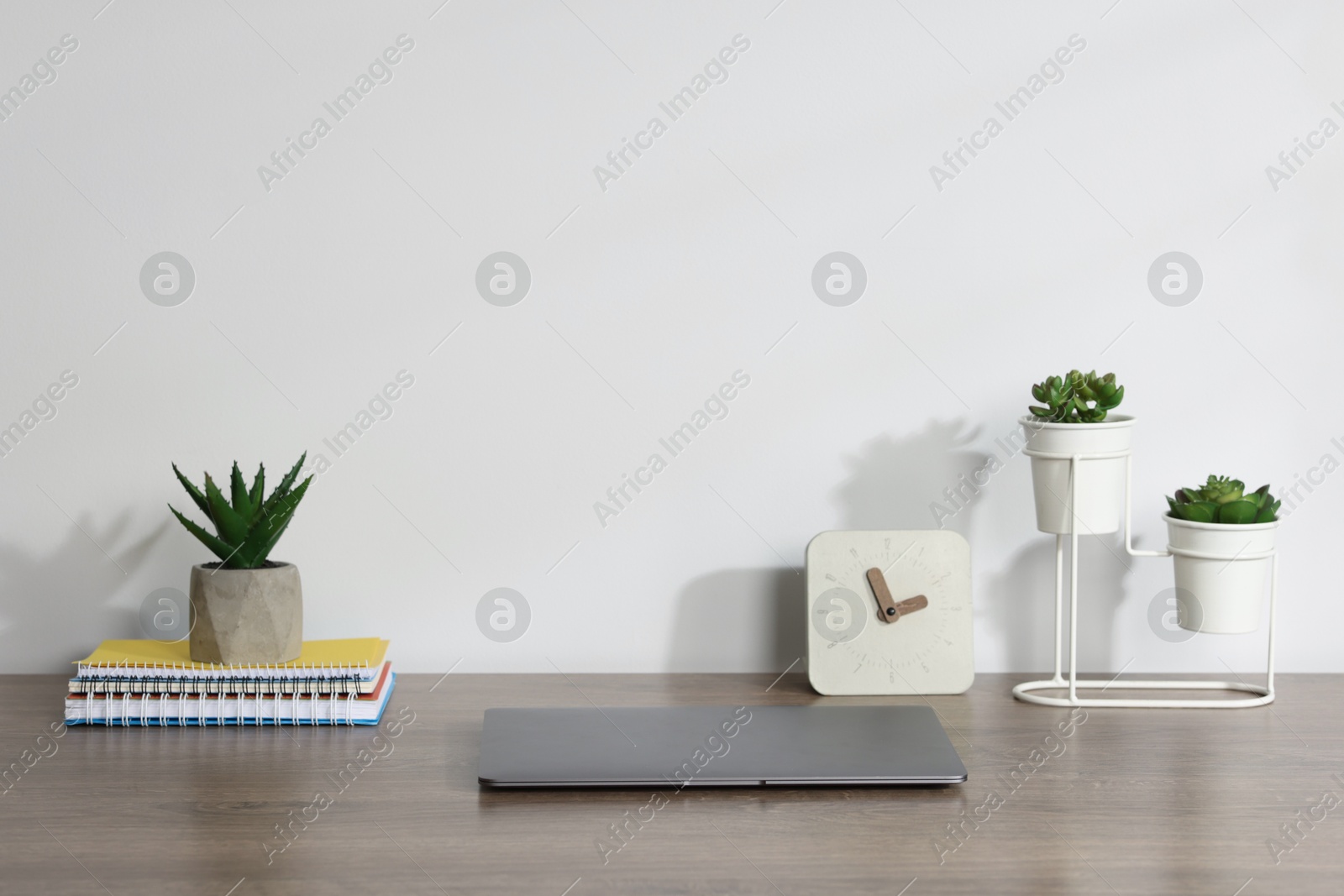 Laptop, stationery, floral decor and alarm clock on wooden office table against white background Photo of Laptop, stationery, floral decor and alarm clock on wooden office table against white background