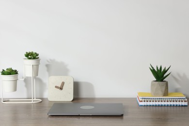 Photo of Laptop, stationery, floral decor and alarm clock on wooden office table against white background