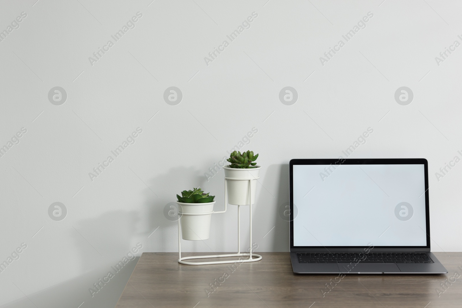 Laptop and floral decor on wooden office table against white background, space for text Photo of Laptop and floral decor on wooden office table against white background, space for text