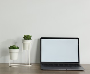 Photo of Laptop and floral decor on wooden office table against white background