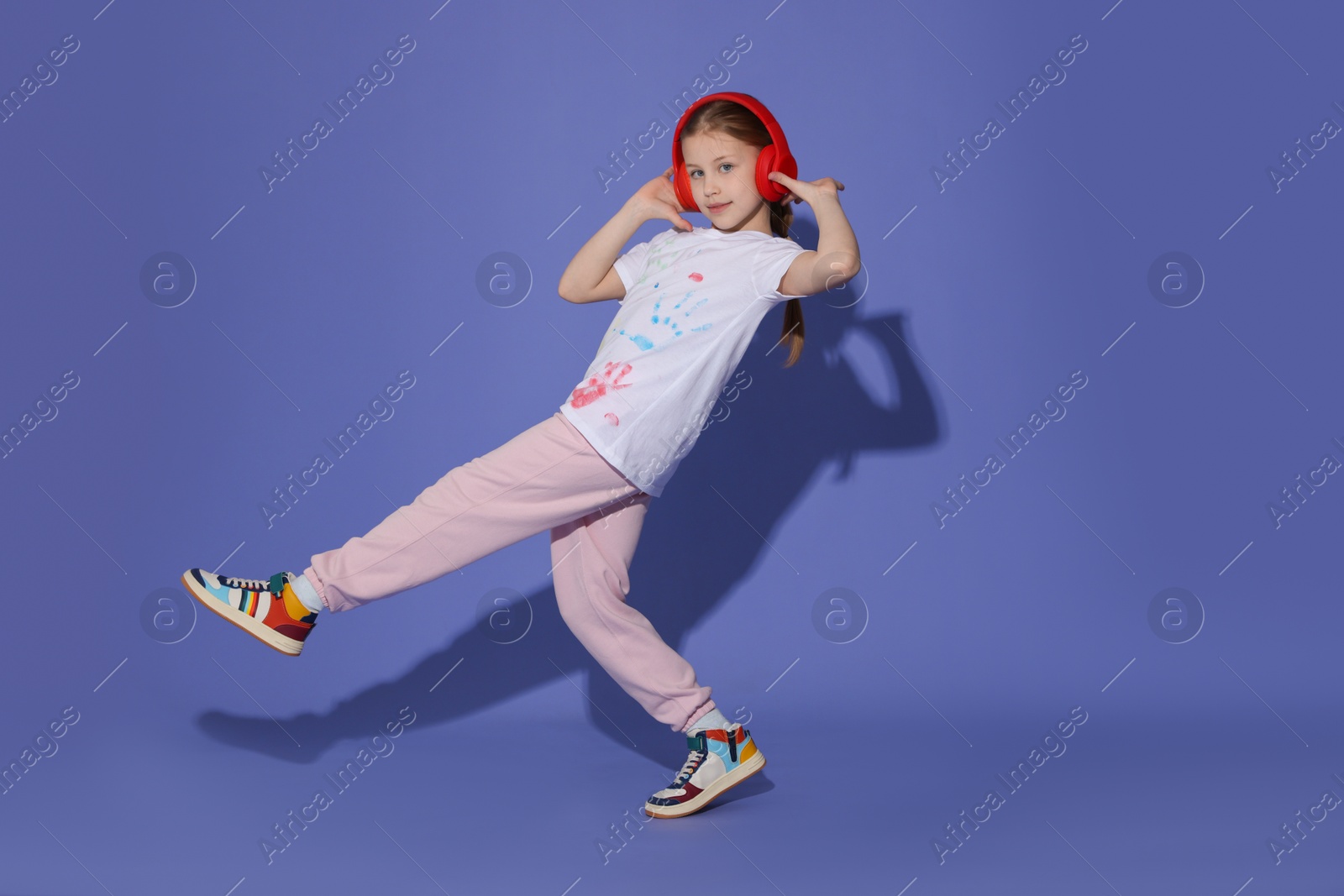 Girl with headphones dancing on purple background Photo of Girl with headphones dancing on purple background