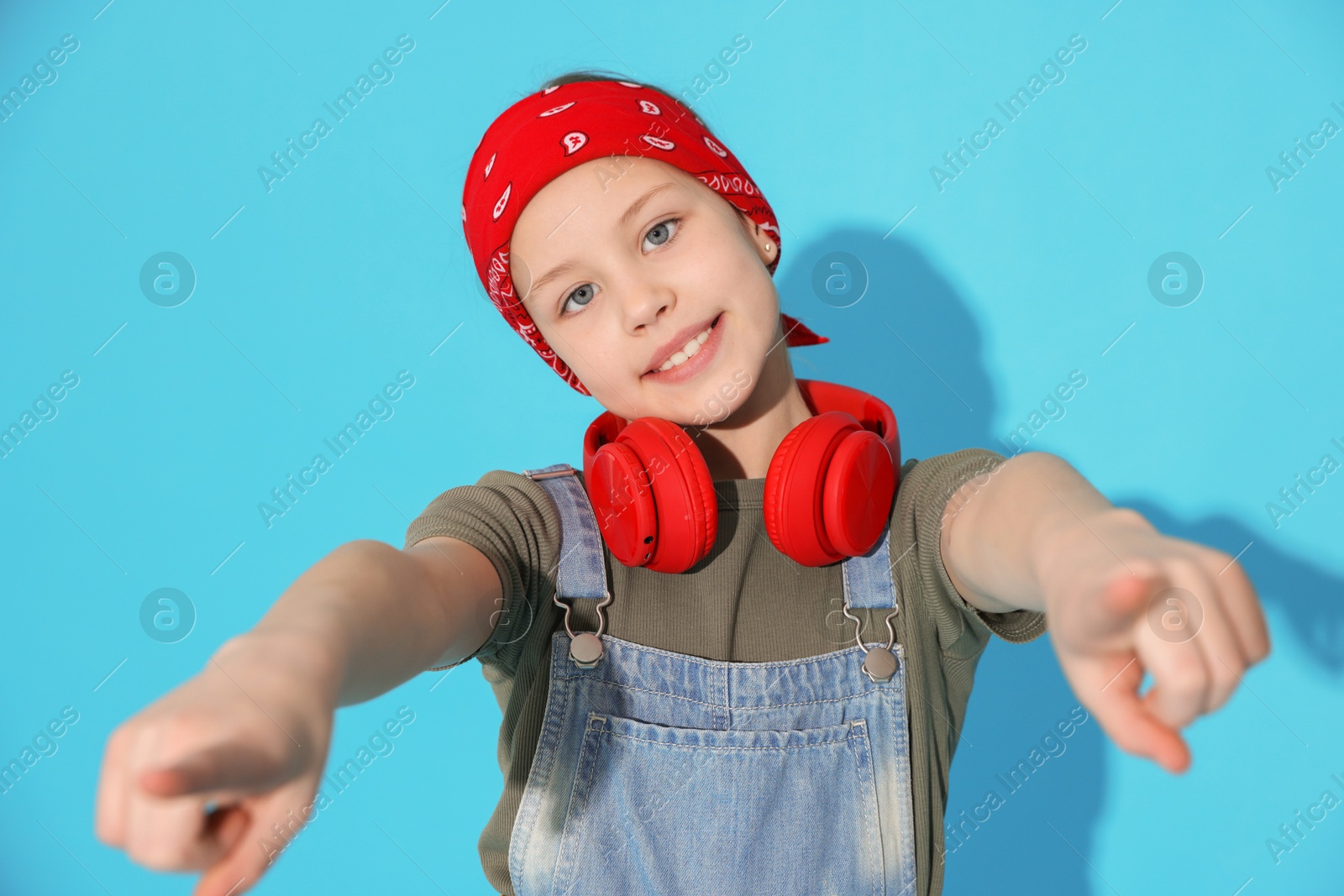 Girl with headphones dancing on light blue background Photo of Girl with headphones dancing on light blue background