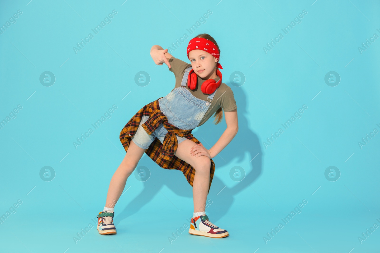 Photo of Girl with headphones dancing on light blue background