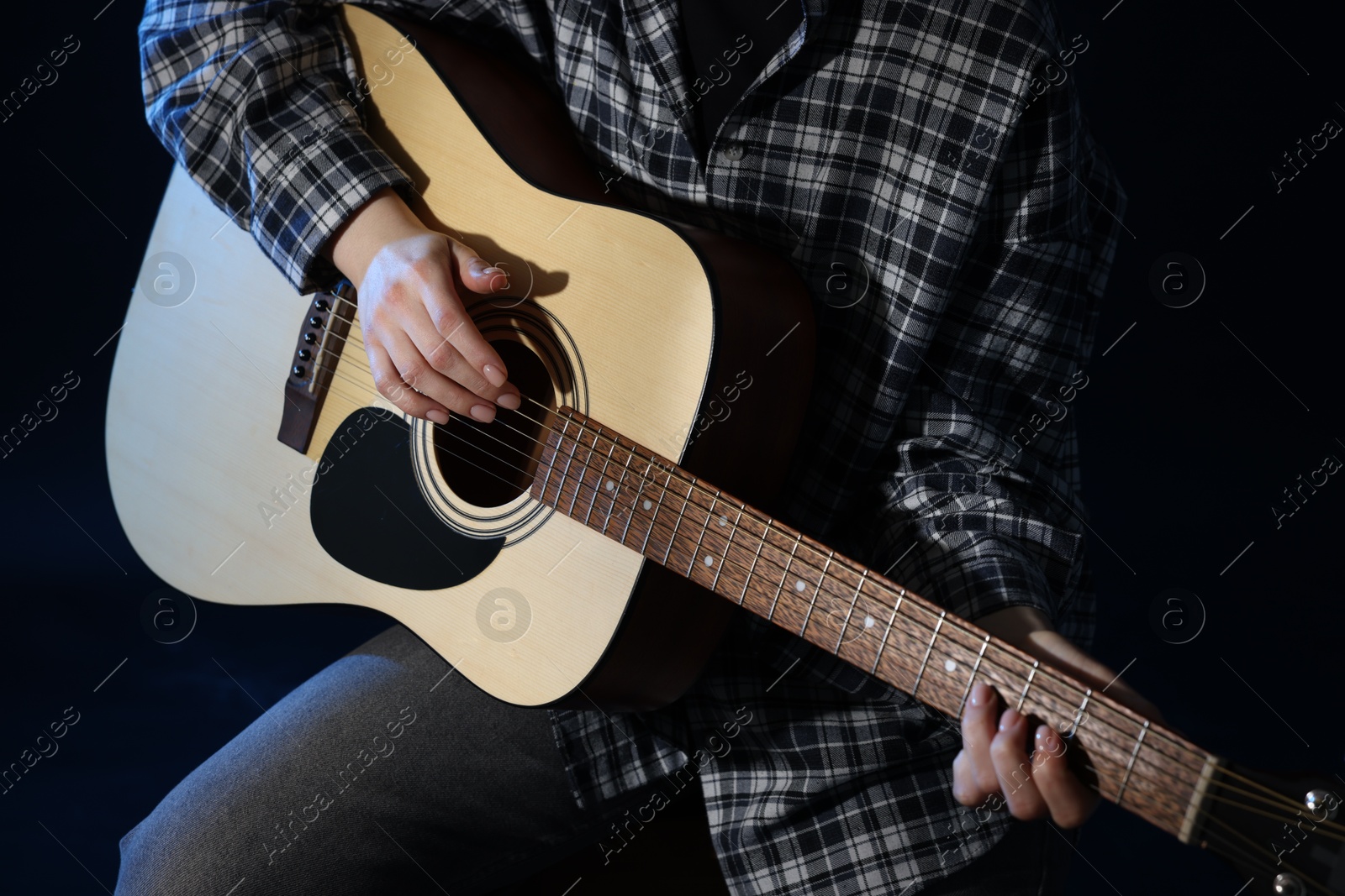 Woman playing guitar on black background, closeup Photo of Woman playing guitar on black background, closeup