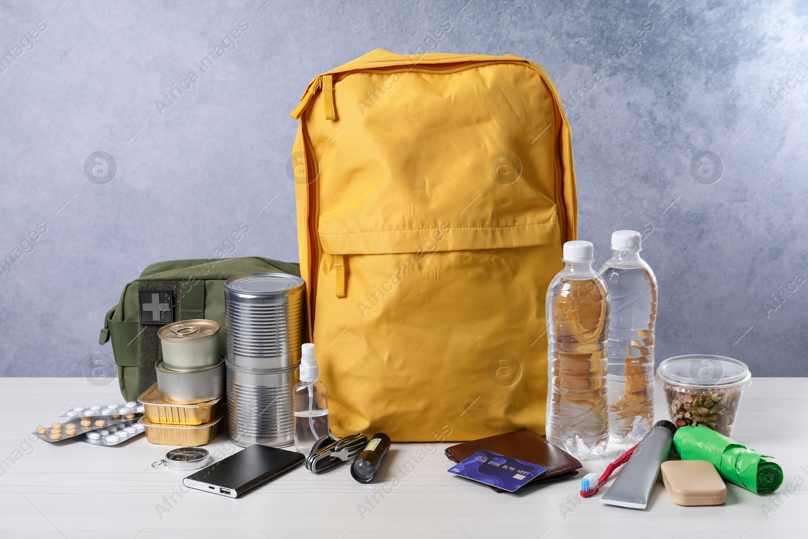 Survival kit. Different emergency supplies on white wooden table Photo of Survival kit. Different emergency supplies on white wooden table