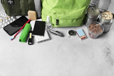 Photo of Survival kit. Different emergency supplies on light table, above view. Space for text
