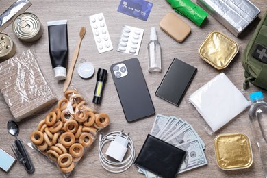 Photo of Survival kit. Different emergency supplies on wooden table, flat lay