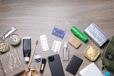 Photo of Survival kit. Different emergency supplies on wooden table, flat lay