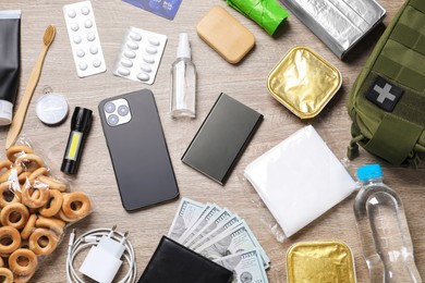 Photo of Survival kit. Different emergency supplies on wooden table, flat lay