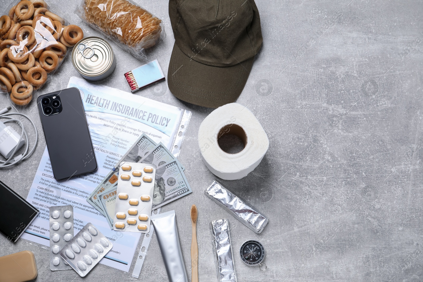 Survival kit. Different emergency supplies on grey table, flat lay. Space for text Photo of Survival kit. Different emergency supplies on grey table, flat lay. Space for text