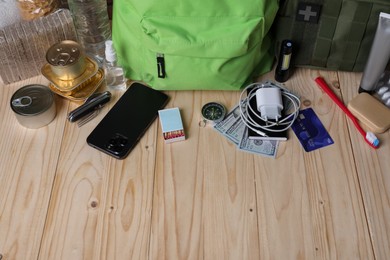 Photo of Survival kit. Different emergency supplies on wooden table, above view. Space for text