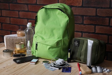 Photo of Survival kit. Different emergency supplies on wooden table near brick wall