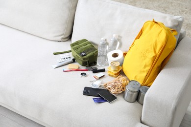 Photo of Survival kit. Different emergency supplies on sofa indoors