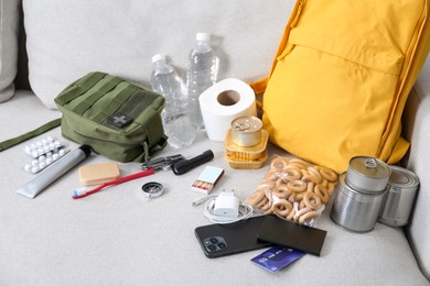 Photo of Survival kit. Different emergency supplies on sofa indoors